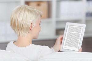 Closeup rear view of a blond young woman reading eBook at home